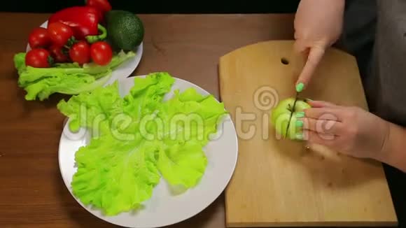 一个女人用一把刀把一个绿色的苹果切成小块时间跨度视频的预览图