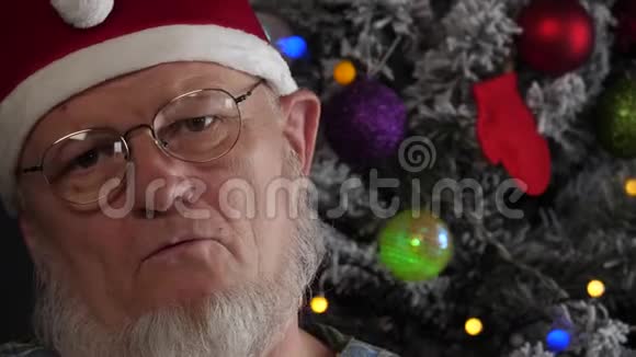 戴着灰色胡子的快乐老人在花环的圣诞树背景上吃着带水的药和饮料片绿色视频的预览图