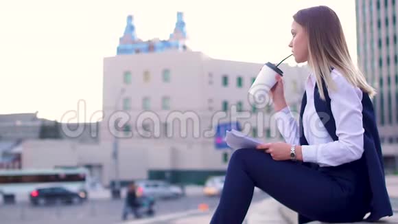 迷人的女孩晚上在市中心穿着西装喝着咖啡拿着文件视频的预览图