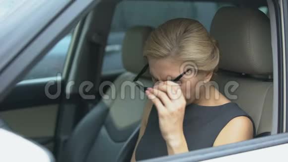 漂亮的女性在汽车上摘下眼镜感到眼痛疲惫视频的预览图