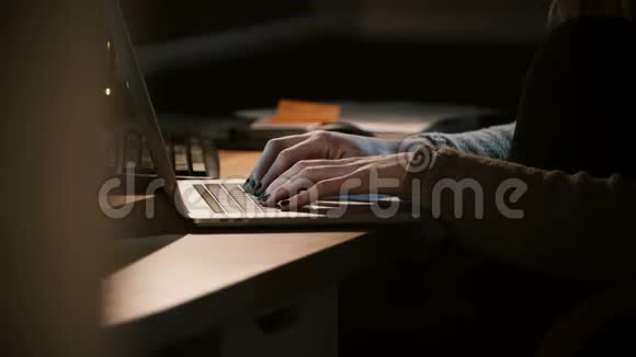 在黑暗中使用笔记本电脑的特写女人的手女性在笔记本键盘上打字移动办公在线侧视4K视频的预览图