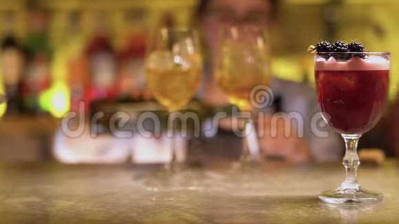 一杯粉红色的鸡尾酒和桑葚酒立在桌子上酒保倒酒视频的预览图