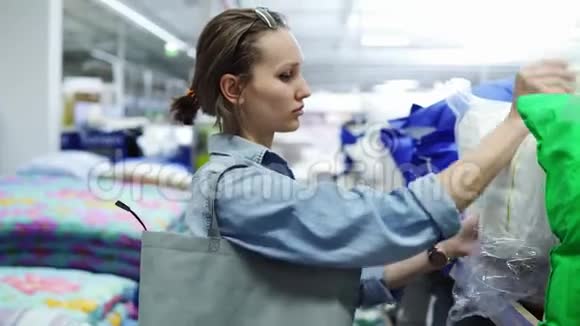 可爱积极的白种人女人在商店里购物概念从架子上拿个软枕头把她的头枕在上面视频的预览图