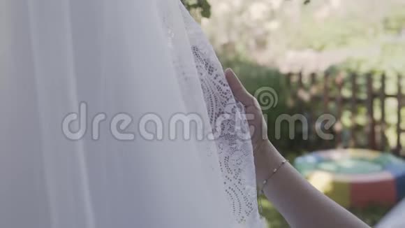令人兴奋的新娘在明亮浪漫的灯光下抚摸和抚摸她的白色漂亮婚纱视频的预览图