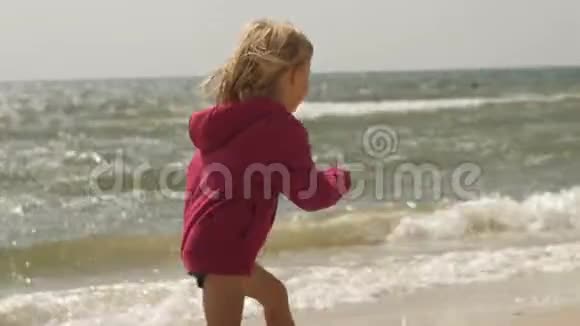 金发碧眼的快乐女孩在海浪的背景下在沙滩上追逐海鸥视频的预览图