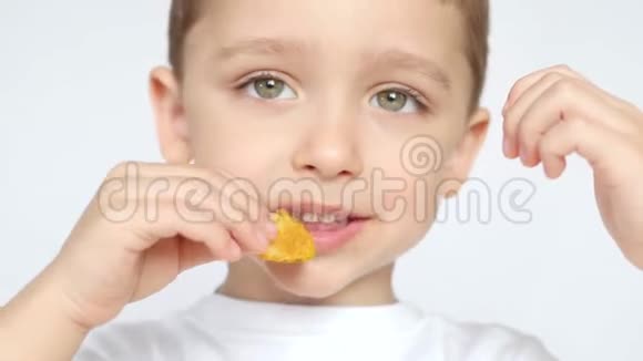 一个高兴又高兴的孩子吃薯片在白色背景上特写视频的预览图