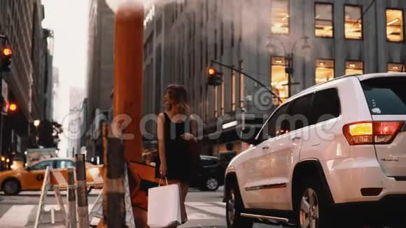 年轻漂亮的女人站在市中心拿着纽约的购物袋靠近烟斗雾气弥漫视频的预览图