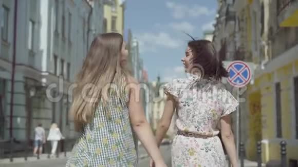 两个兴高采烈的女人带着购物袋穿过城市街道年轻女孩穿着时髦的夏装视频的预览图