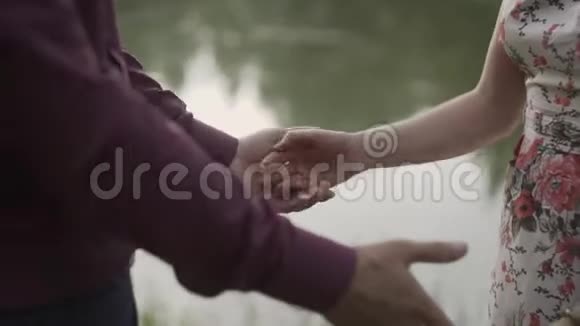 亲密的两个情人携手日落湖背景下男女牵手的细节轮廓视频的预览图