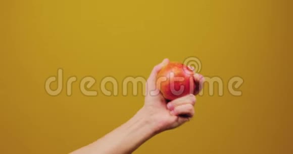 雄性手在工作室的黄色背景上旋转红色多汁苹果保健健康生活方式水果视频的预览图