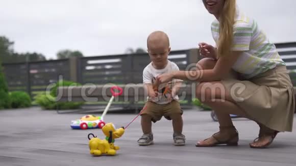 年轻的母亲在花园里玩和她的小儿子兄弟玩玩具家庭价值观暖色视频的预览图