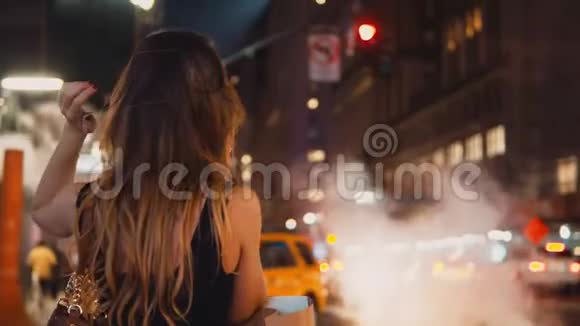 美国纽约一个年轻快乐的女人晚上站在市区的交通中用手机聊天视频的预览图