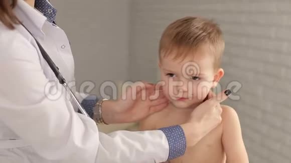 一位年轻女子儿科医生检查一个孩子的喉咙和淋巴结视频的预览图