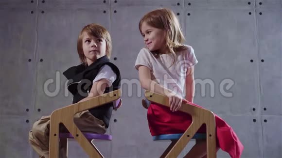 小男孩和小女孩坐在房间里的木椅上笑着视频的预览图