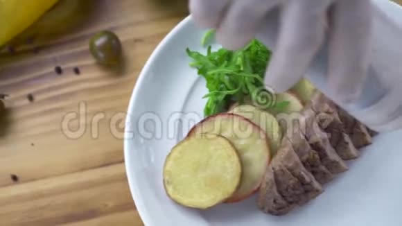 厨师用烤肉和蔬菜装饰在白色盘子上倒入酱汁高级菜肴的食品造型和设计视频的预览图