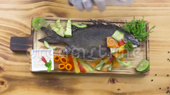海餐馆用蔬菜烤鱼厨师用木制的新鲜蔬菜浇上炸鱼的酱汁视频的预览图