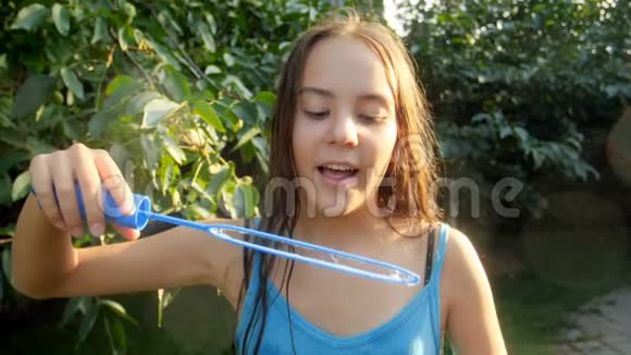 公园里微笑的少女在镜头中吹肥皂泡的慢动作视频视频的预览图