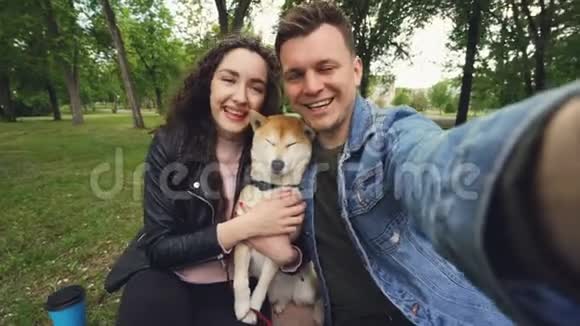 两个快乐的人和小狗在公园里自拍亲吻和爱表达爱和关怀的观点视频的预览图