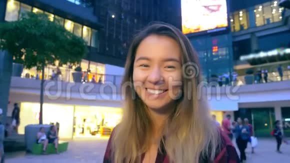 美丽微笑的东亚女孩的肖像背景中是一家大型超市模糊的灯光视频的预览图