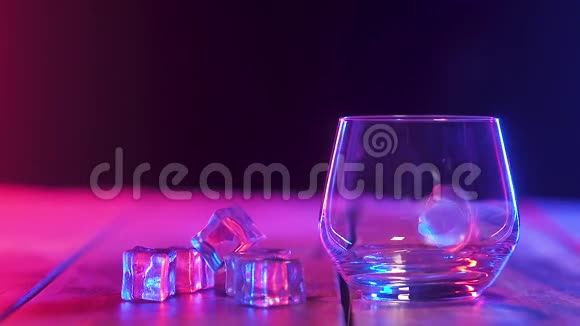 空杯子里掉落的冰块互相弹跳彩色照明特写镜头视频的预览图