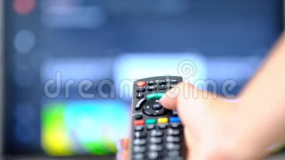 慢动作的女人看电视按下遥控器上的按钮手拿着电视遥控器关掉视频的预览图