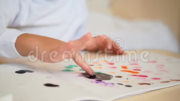 孩子的手在纸上画画手指浸入油漆导致染色特写镜头视频的预览图