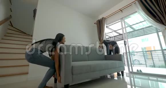 幸福的亚洲年轻夫妇搬进新房子时搬沙发视频的预览图