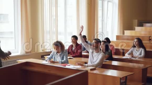 聪明的学生正在举手和教授交谈而其他学生则在倾听他们微笑着视频的预览图