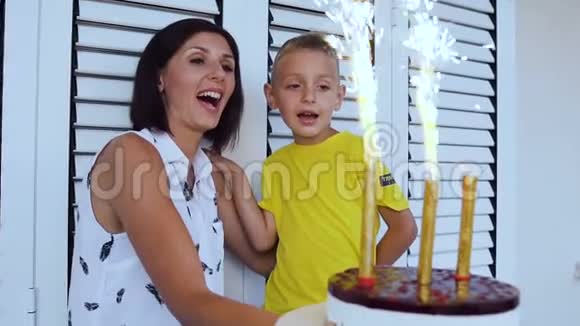 快乐的小男孩许愿和妈妈一起吹灭生日蛋糕上的蜡烛庆祝儿子的生日视频的预览图
