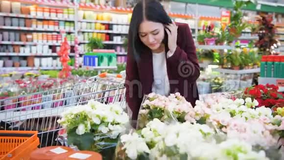 美丽的深色头发的年轻女子在花园商店超市里闻着鲜花女园丁手轻轻地抚摸着视频的预览图