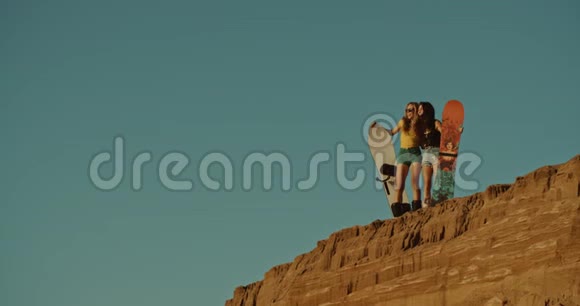 两个性感的女孩在沙漠里拿着沙板视频的预览图
