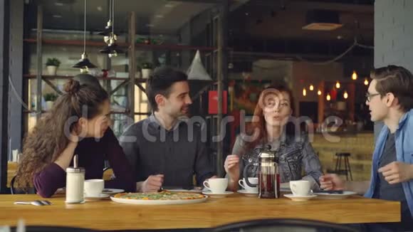 快乐又迷人的一群男女朋友正在一家小咖啡馆或披萨店里一起聊天和欢笑视频的预览图