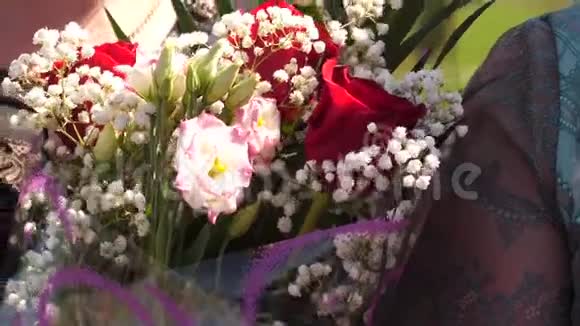鲜花作为节日的礼物花束在一个美丽的花朵和红玫瑰的女人手中特写镜头视频的预览图