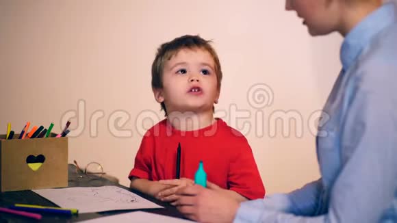 这个男孩正和一位老师在灰色背景下画画学习观念穿制服的学童视频的预览图