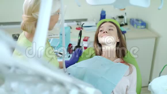 在牙医办公室做定期牙科检查的女人戴牙椅的快乐女孩视频的预览图