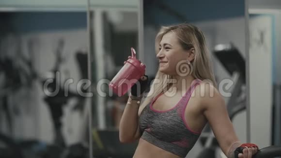在健身房喝蛋白质的漂亮女孩运动后女性饮用水视频的预览图