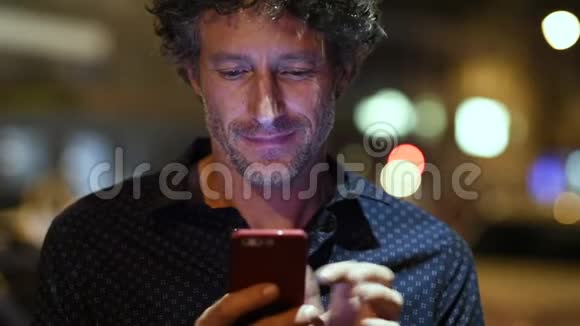 男人晚上检查智能手机视频的预览图