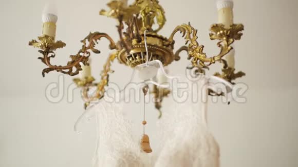 金色老式吊灯上挂着的奶油婚纱倾斜镜头视频的预览图