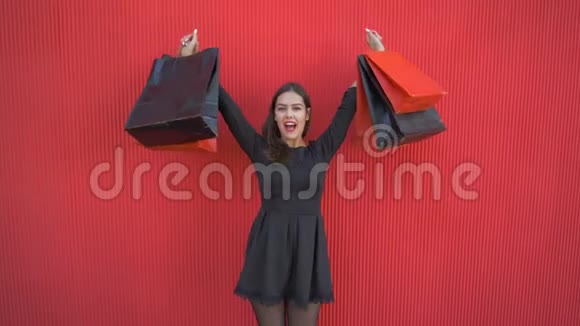 快乐的购物者女孩在黑色星期五的季节性促销活动中举起购物袋从快乐中跳舞视频的预览图