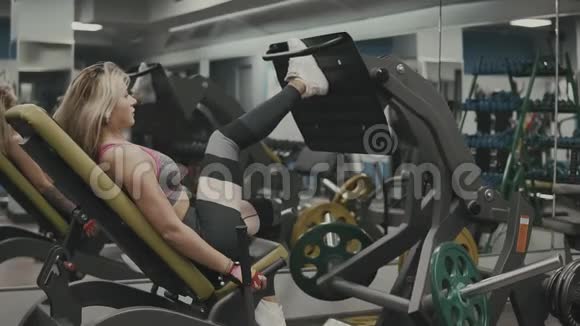 强壮的女孩在健身房里从事腿部肌肉的运动训练装置视频的预览图