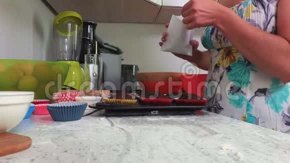 女人用糖粉把纸杯蛋糕的顶部撒起来视频的预览图