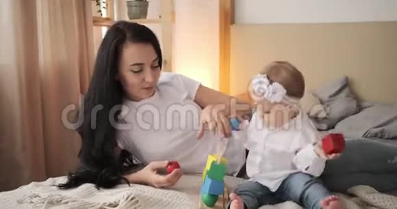 妈妈和小女儿在床上玩玩具积木视频的预览图