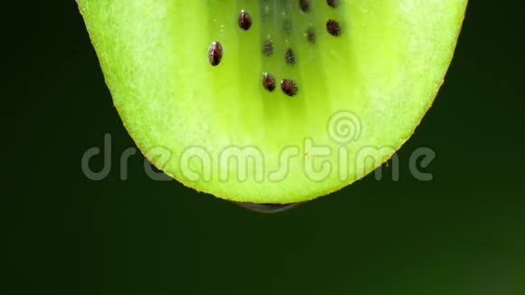 一片猕猴桃的近缘或宏观一滴水缓慢地落下黑色背景视频的预览图