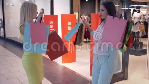 购物快乐的女性朋友在购物中心的销售季节在昂贵的商店打折购物后跳舞发短信视频的预览图