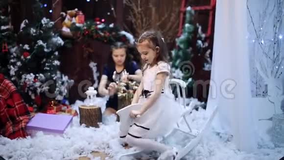 一个女孩骑着一匹木马在一棵圣诞树旁孙女们把一条白色的披肩作为礼物送给心爱的人视频的预览图