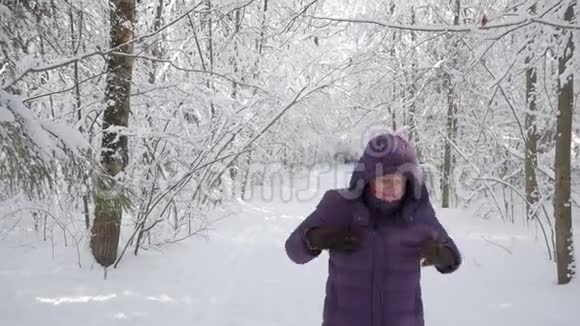 一位老妇人在冬天的森林里摇雪视频的预览图