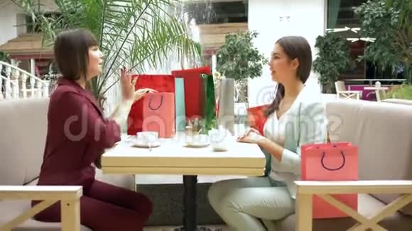 购物时喝咖啡休息时尚女士在餐厅喝茶吹嘘在季节性销售和视频的预览图