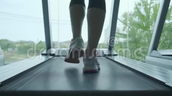 女人肌肉发达的腿在健身房跑步机上特写视频的预览图