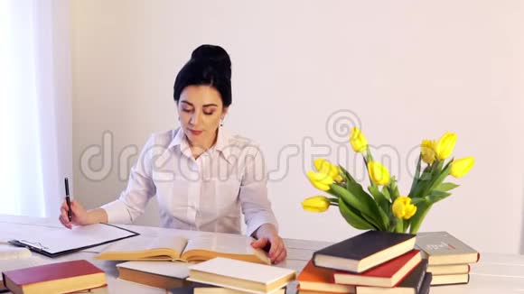 工作太累了困倦的年轻女人坐在书桌前拿书视频的预览图