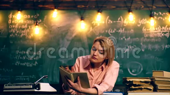 一个女人在学校班上读一本书学习观念穿制服的学童教室里的老师视频的预览图